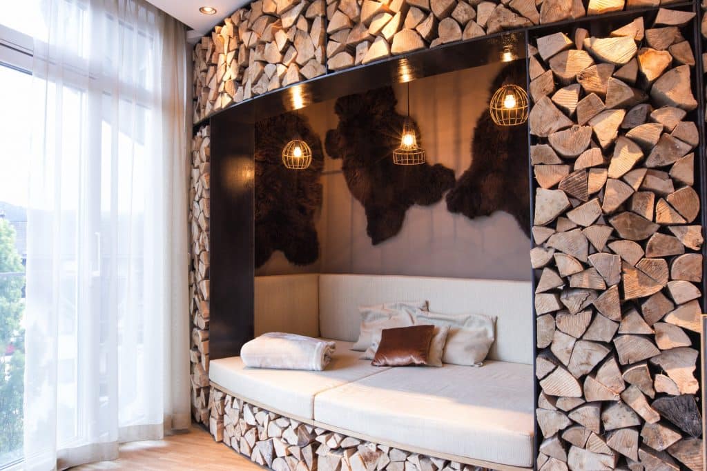 Gemütliche Liegeecke mit aufgeschichtetem Holz und warmer Beleuchtung