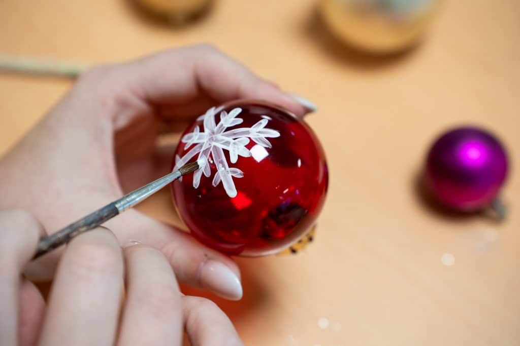 handbemalte Weihnachtskugel in rot mit einer weißen Schneeflocke als Motiv in der Familotel Sonnenpark Kreativwerkstatt