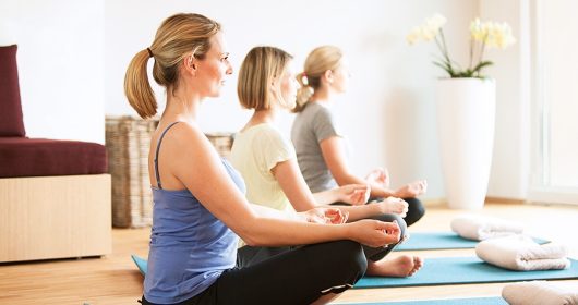 Frauen sitzen im Lotussitz auf Yogamatten