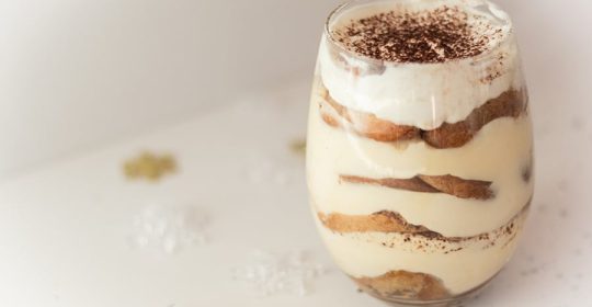 Schichtdessert in einem Glas auf weißem Tisch