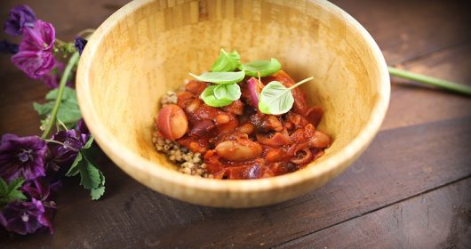 Bohneneintopf in einer hellen Holzschale mit Basilikum garniert