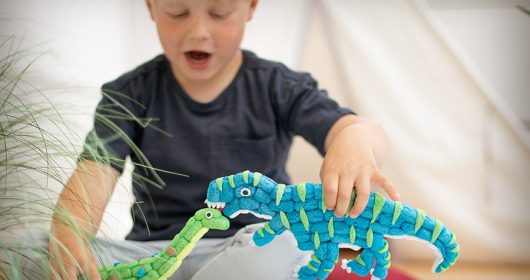 Junge spielt mit zwei Dinosaueriern aus Playmais
