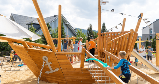 hölzernes Piratenschiff auf Spielplatz mit spielenden Kindern