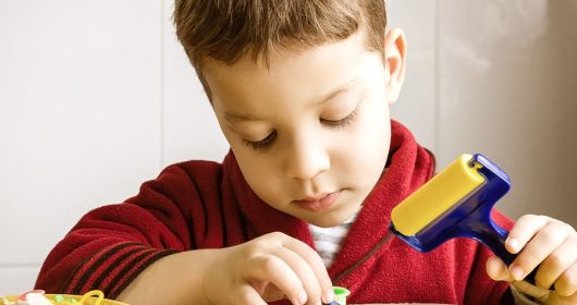 Junge in roter Jacke knetet auf dem Tisch