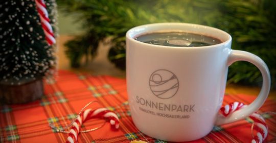 Glühwein in weißer Tasse umgeben von weihnachtlicher Dekoration