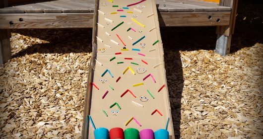 Murmelbahn aus bunten Eisstielen, Pappe und bunten Pappbechern auf einem Hackschnitzelfeld