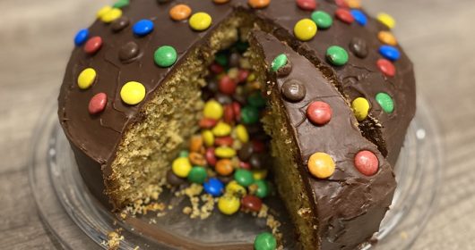 Schokoladenkuchen garniert mit bunten Smarties auf einem gläsernen Teller