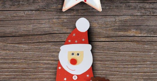 Weihnachtsmann aus Tonkarton gebastelt auf Holz unter Weihnachtssternen