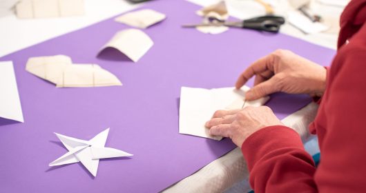 In der Kinderbetreuung vom Familotel Sonnenpark wird mit weißem Geschenkpapier ein Origami-Stern gefaltet