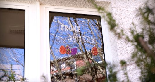 Fenster bemalt mit bunten Ostereiern und "Frohe Ostern"