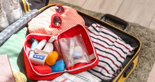 Koffer mit Reiseapotheke und Kleidung