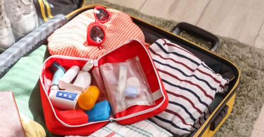 Koffer mit Reiseapotheke und Kleidung