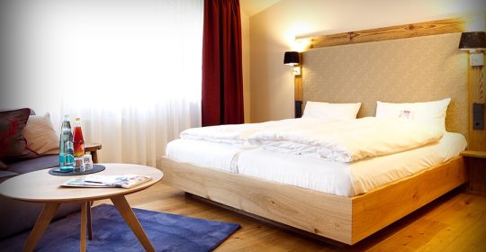 Doppelbett auf Holzboden in einem Schlafzimmer mit Sofa und Tisch