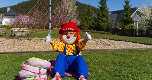 Clown "Happy" absolviert Sportübgungen bei Sonnenschein auf dem Rasen