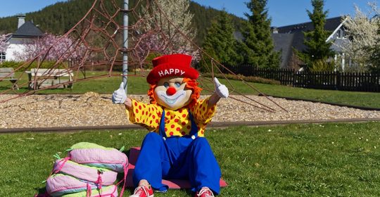 Clown "Happy" absolviert Sportübgungen bei Sonnenschein auf dem Rasen