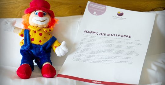 Plüschfigur eines Clowns liegt neben einer Gute Nacht Geschichte auf einem Kopfkissen