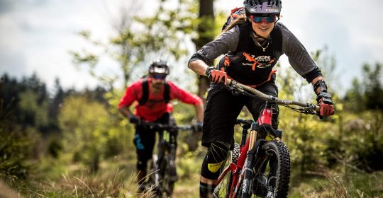 Mann und Frau auf Mountainbikes fahren durch den Wald