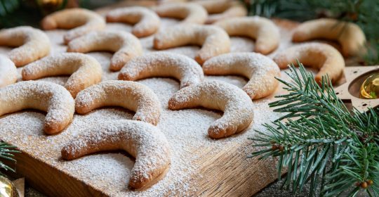 Vanillekipferl auf einem Holzbrett mit Puderzucker bestreut