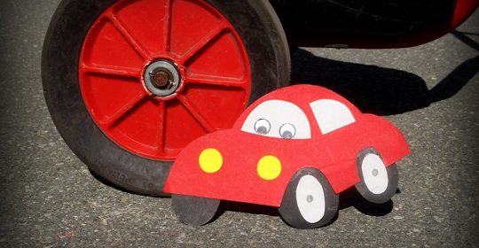 rotes Auto aus Tonkarton gebastelt steht neben einem roten Reifen aus Asphalt