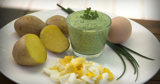 Weiße Teller mit gekochten Eiern und Kartoffeln, sowie grüner Soße