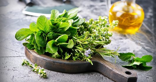 Verschiedene Kräuter auf einem runden Holzbrett auf Steintisch