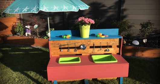 Matschküche im Garten mit Geschirr und grünen Waschbecken