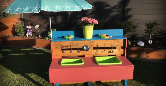 Matschküche im Garten mit Geschirr und grünen Waschbecken