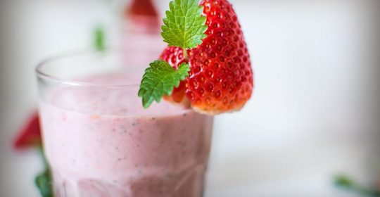 Minzzweige in Erdbeere, welche auf einem Glas Erdbeer-Milchshake befestigt ist