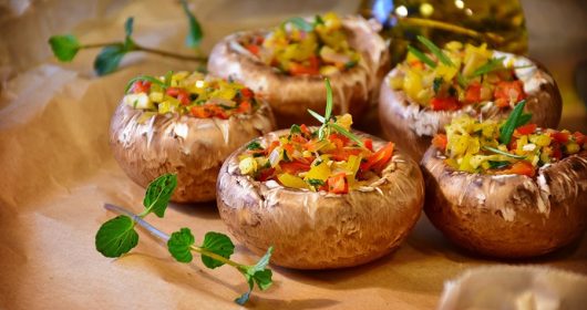 Mit Paprika gefüllte Champignons auf Backpapier