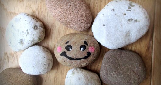 bemalte Steine liegen auf einem Holztisch