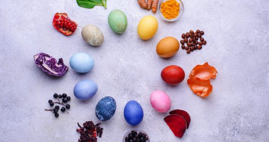 Bunte Ostereier mit natürlicher Eierfärbemethode gefärbt liegen im Kreis mit Obst und Gewürzen