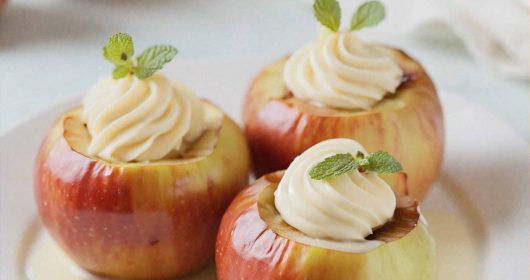 Traditioneller Bratapfel mit Marzipanfüllung und Vanillesoße auf einem weißen Teller