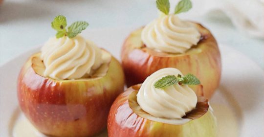 Traditioneller Bratapfel mit Marzipanfüllung und Vanillesoße auf einem weißen Teller