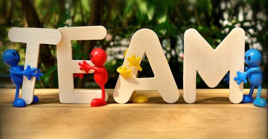 bunte Holzfiguren halten das Wort "Team"