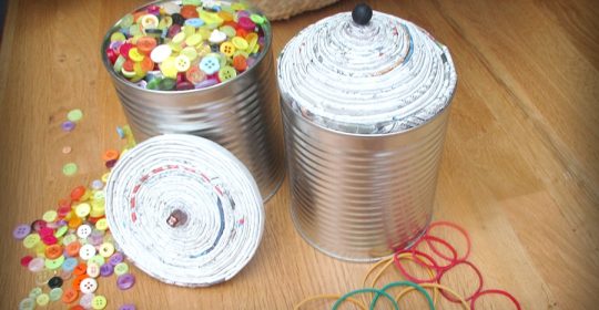 Blechdosen gefüllt mit Knöpfen auf einem Holztisch