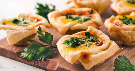 Vegetarische Shakshouka-Taschen mit Petersilie auf einem Holzbrett