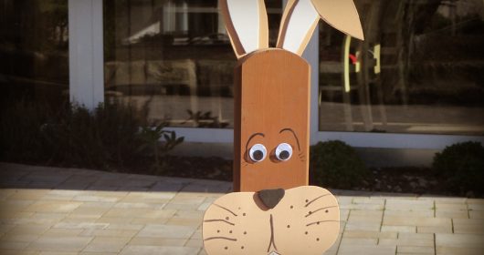 Zaunlattenfigur als brauner Hase vor einem Fenster