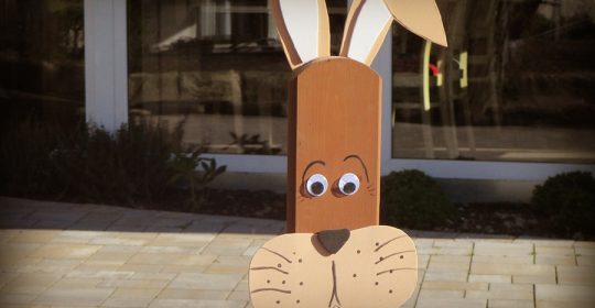 Zaunlattenfigur als brauner Hase vor einem Fenster