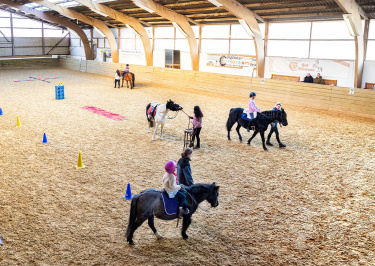 Kinder reiten auf Ponys in der Reithalle