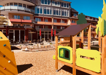 Spielplatz und im Hintergrund ist das Restaurant mit der Terrasse